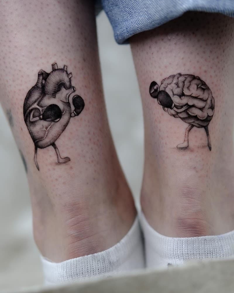 Twee tattoos op enkels: een boksend anatomisch hart en een boksend brein.