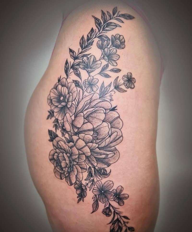 Grote fineline bloemen tattoo op heup en bovenbeen.
