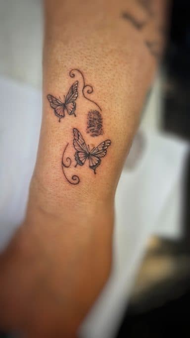 Twee vlinders, een vingerafdruk en sierlijke krullen op een enkel.
