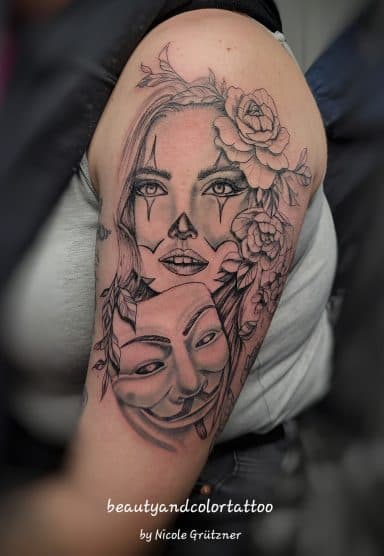 Vrouw met clownsmake-up, Guy Fawkes masker en bloemen op bovenarm.