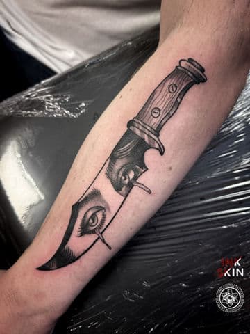 Zwart-wit tattoo van een dolk met huilende ogen op het lemmet.