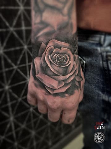Zwart-grijze realistische roos tattoo op de hand.