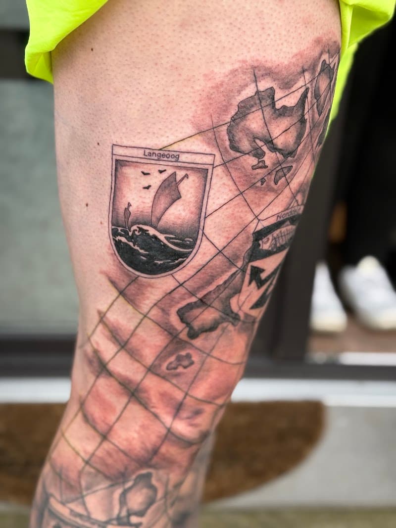 Blackwork tattoo van Langeoog wapenschild en kaart op bovenbeen.