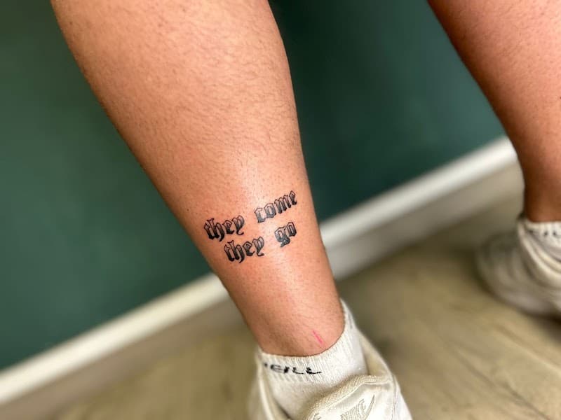 "They come they go" tekst tattoo in gotische stijl op enkel.