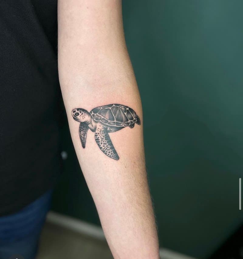 Gedetailleerde zwart-wit zeeschildpad tattoo op de onderarm.