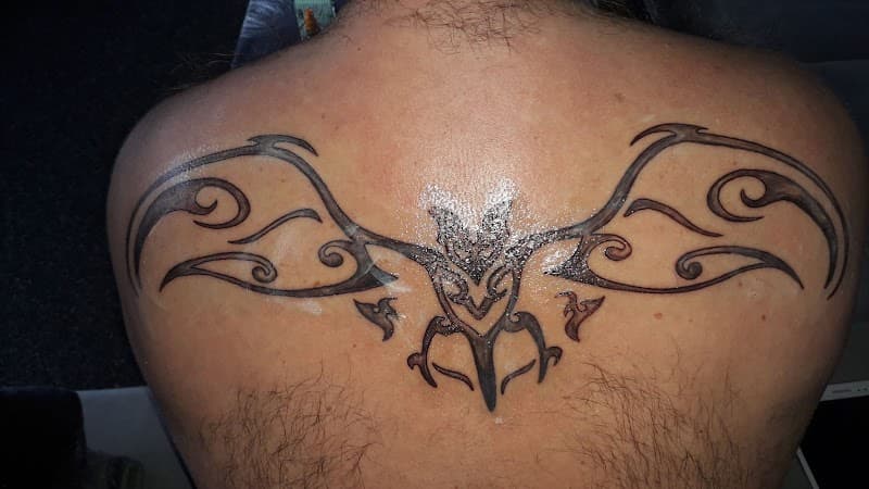 Grote tribal vleermuis tattoo op de bovenrug.