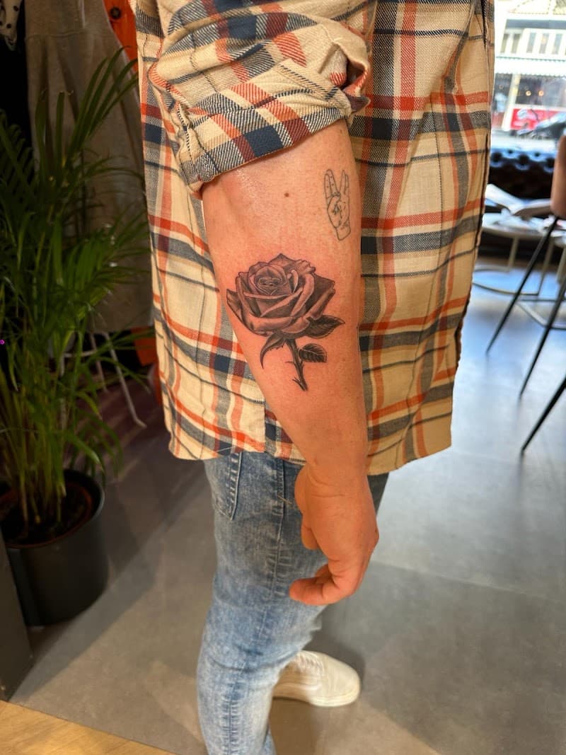 Gedetailleerde zwart-wit roos tattoo op de onderarm.