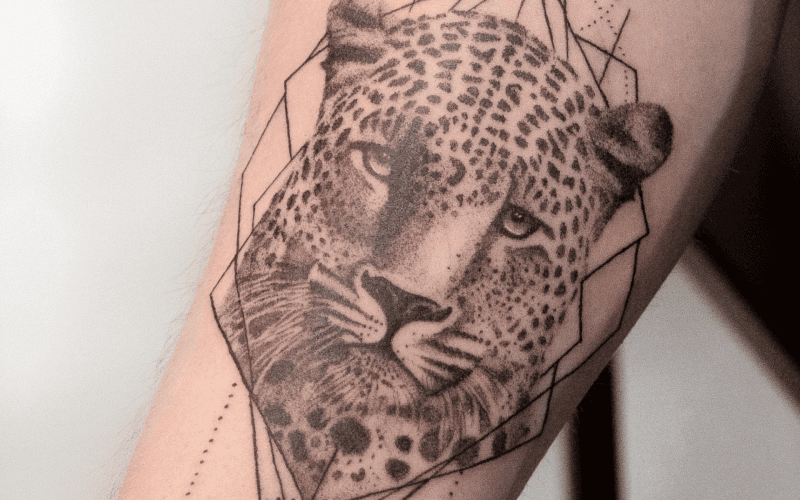 Realistische luipaardkop met geometrische lijnen op onderarm.