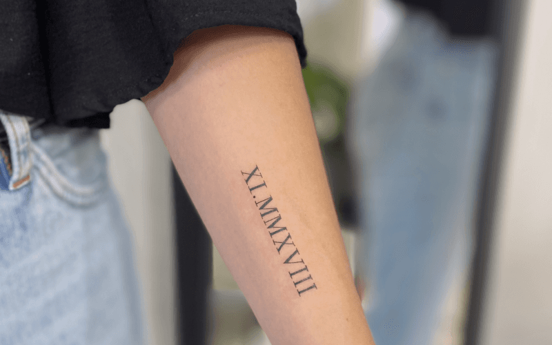 Romeinse cijfers XI.MMXVIII op onderarm