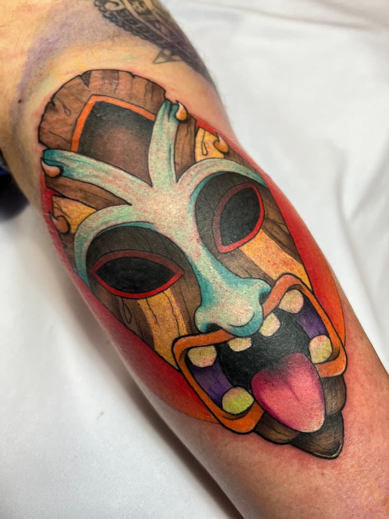 Kleurrijke neo-traditional tiki masker tattoo op het onderbeen.