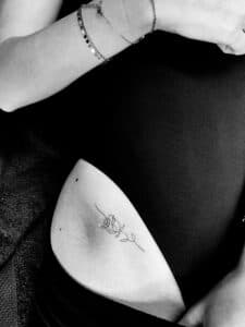 Kleine fineline roos tattoo op de zijkant van de heup.