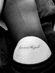 Fineline tekst 'focus on the good' op onderrug.