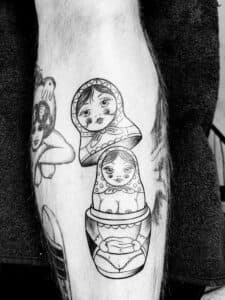 Zwart-wit tattoo van een open Matryoshka pop op een onderbeen.