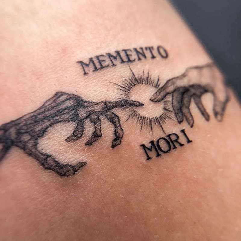 Schetsmatige 'Memento Mori' tattoo met twee handen die elkaar bijna raken.