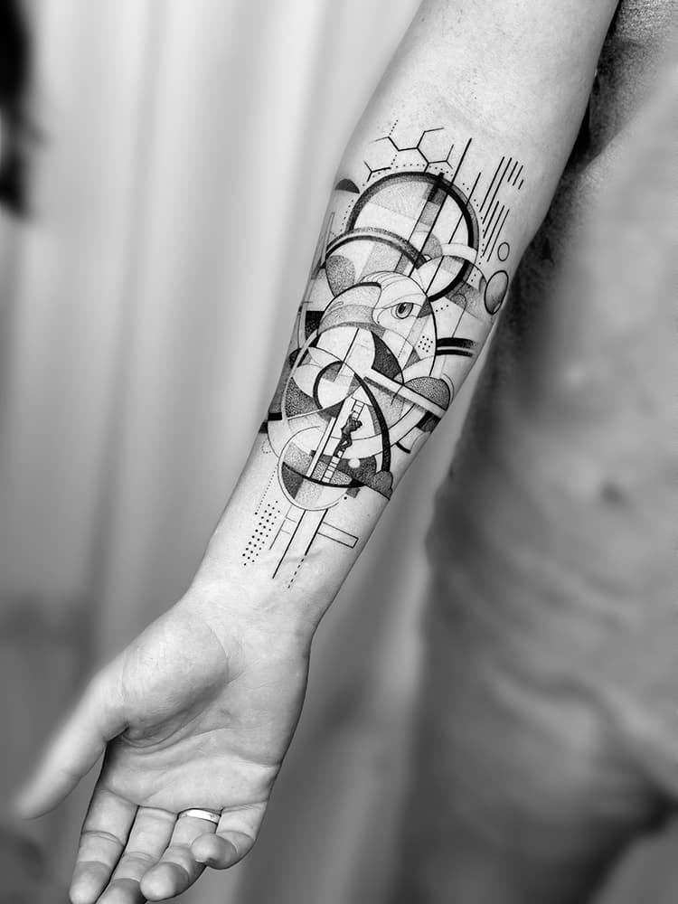 Geometrische abstracte tattoo op onderarm met lijnen, cirkels en een figuur.