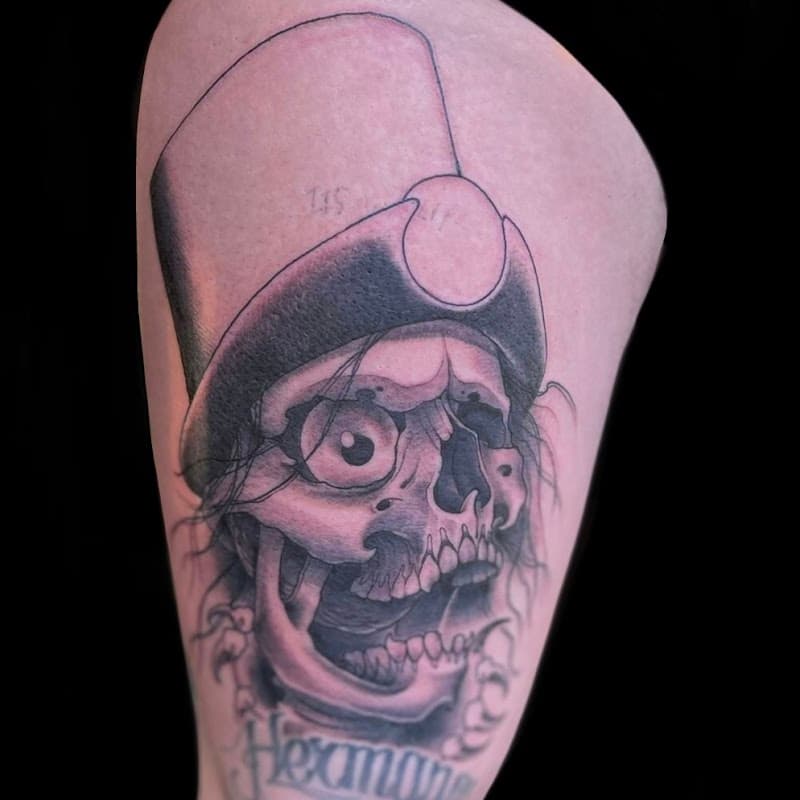 Zwart-wit tattoo van een schedel met een hoge hoed en een groot oog.