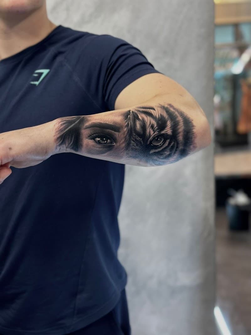 Realistische tattoo van een vrouwen oog en een tijgeroog op de onderarm.