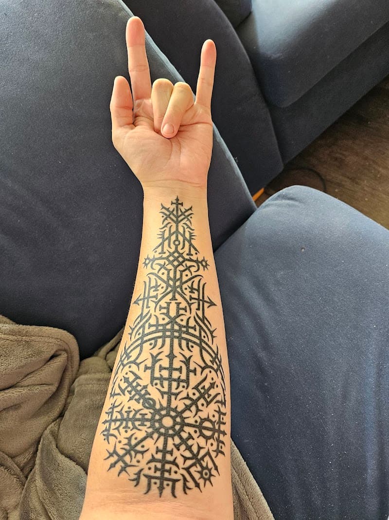 Grote zwarte Noorse runen en Vegvisir kompas op onderarm.