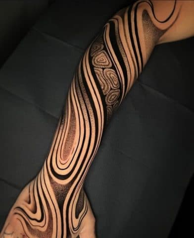 Abstracte zwarte lijnen en dotwork patronen op een volledige arm sleeve.