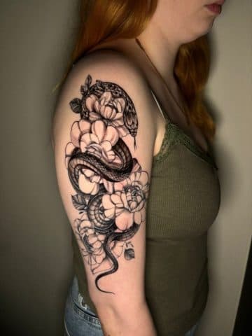 Zwart-wit slang en pioenrozen op bovenarm.