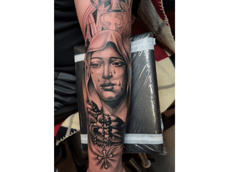 Realistische zwart-wit tattoo van huilende Maagd Maria met rozenkrans.