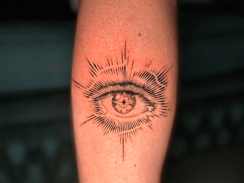 Blackwork tattoo van een oog met stralenkrans op de onderarm.