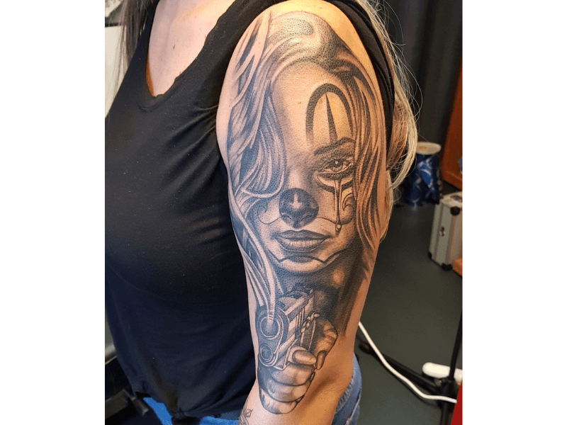 Realistisch portret van een vrouw met clownsmake-up en een pistool.