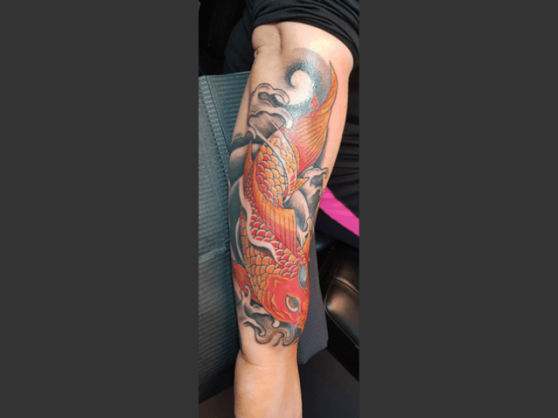 Japanse koi karper tattoo met golven op onderarm