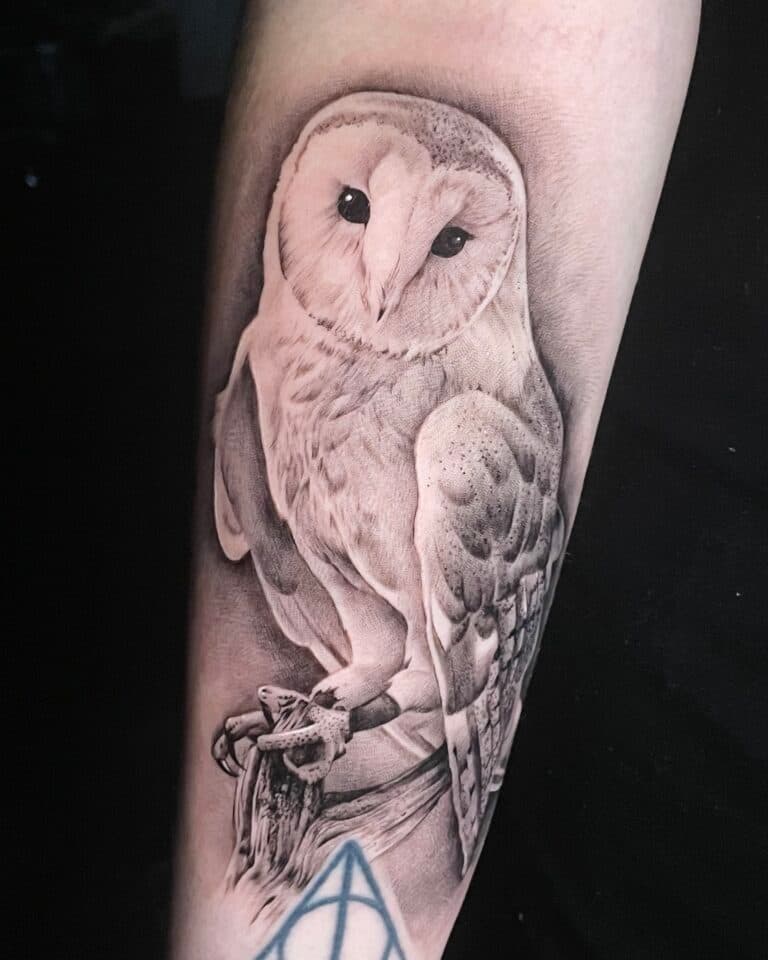 Realistische kerkuil tattoo in zwart-wit op de onderarm.
