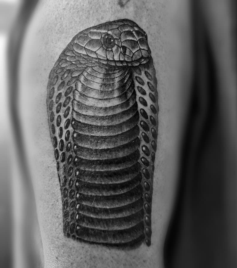Close-up van een gedetailleerde cobra kop tattoo in zwart-wit.