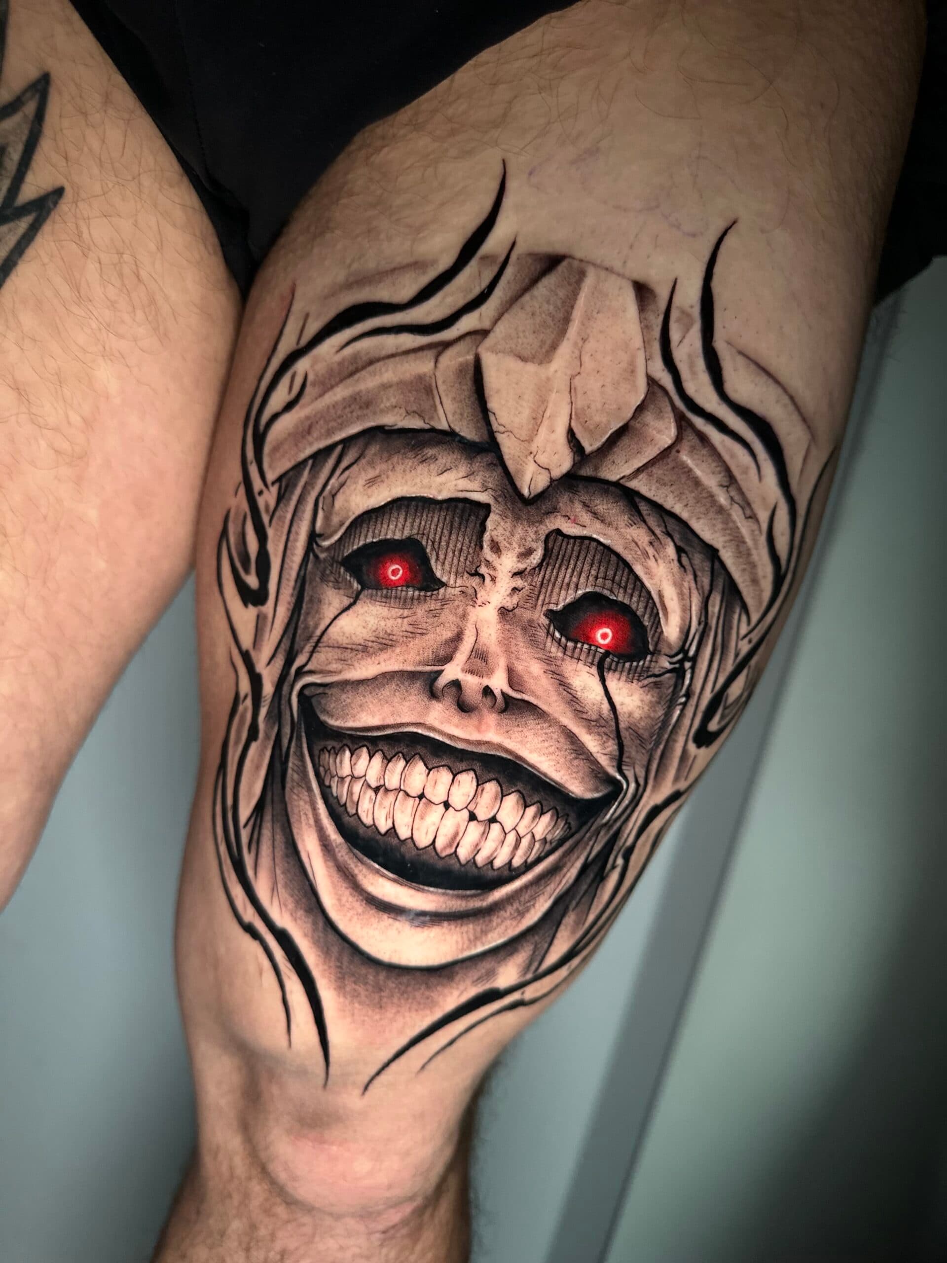 Griezelig standbeeld gezicht met rode ogen op bovenbeen.