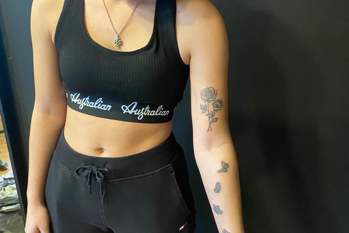 Fineline roos en vlinders op de bovenarm en onderarm.