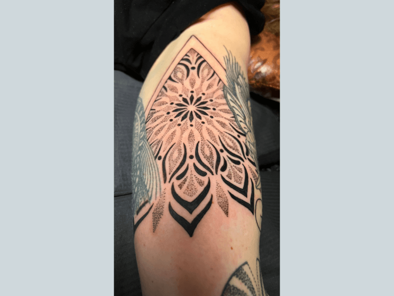 Grote geometrische mandala tattoo met dotwork op de bovenarm.