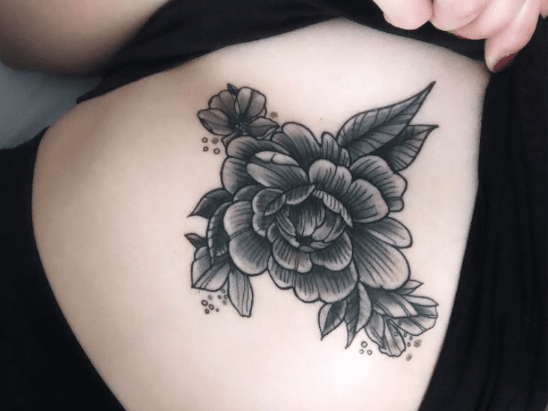 Blackwork pioenroos tattoo op de ribben.