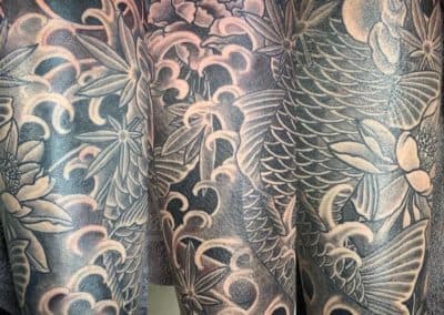 Grote Japanse koi karper tattoo met golven, lotus en esdoornbladeren.