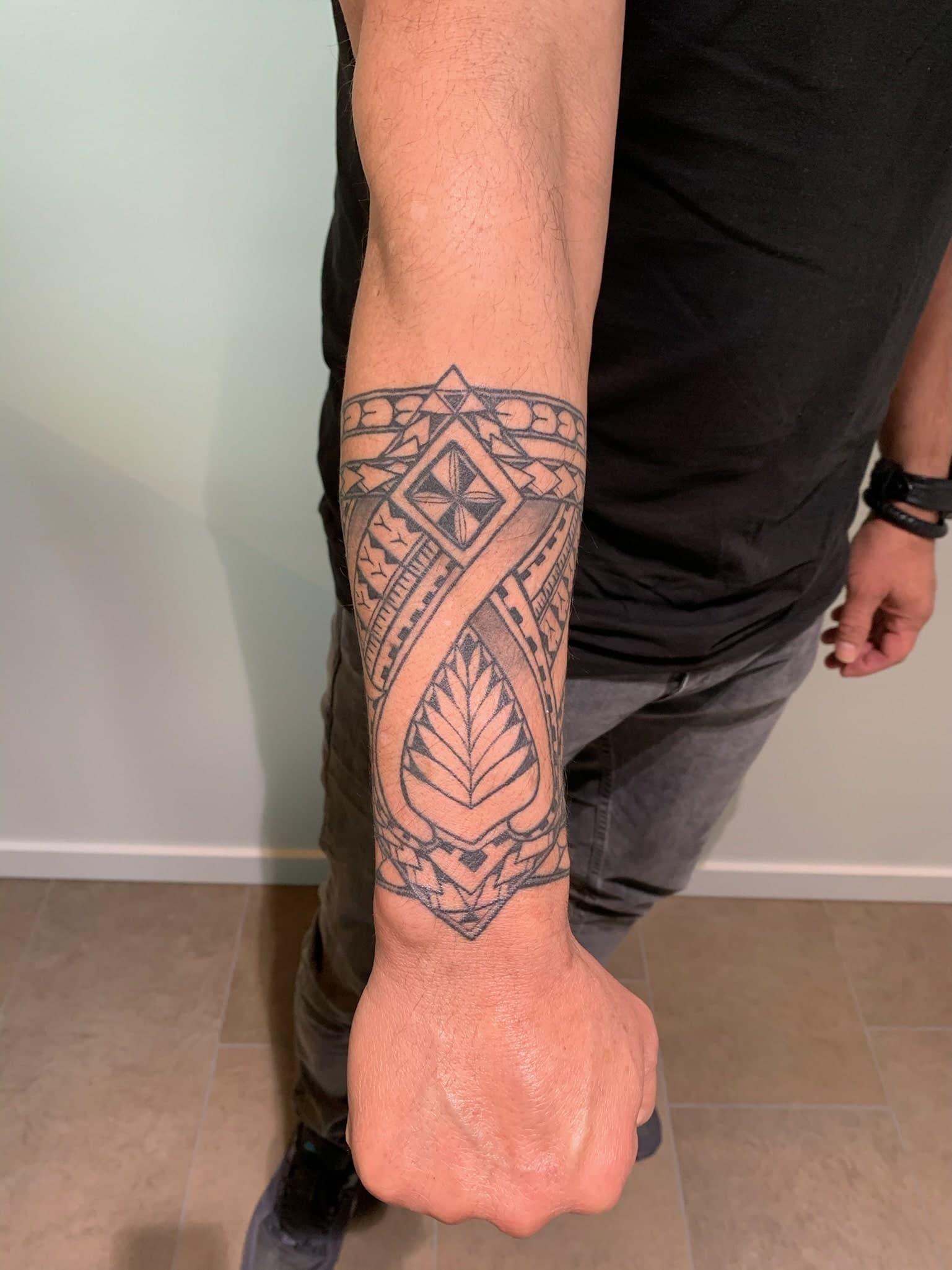 Geometrische tribal band tattoo op onderarm.