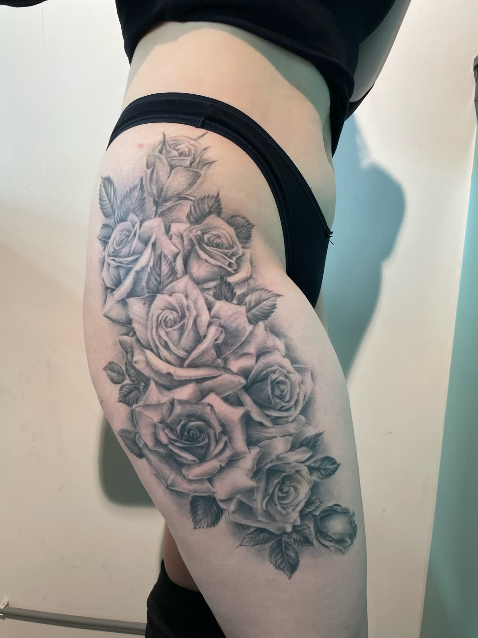 Grote zwart-wit realistische rozen tattoo op bovenbeen.