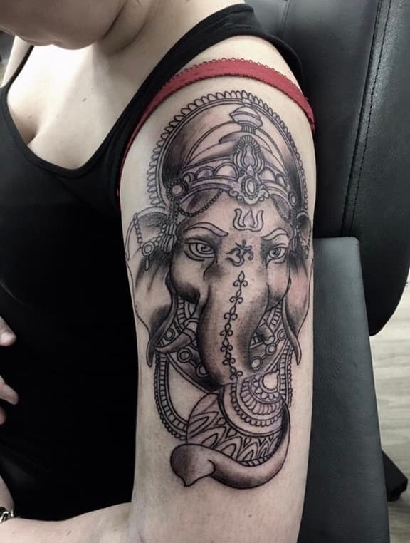 Zwart-wit Ganesha tattoo met sierlijke details op de bovenarm.