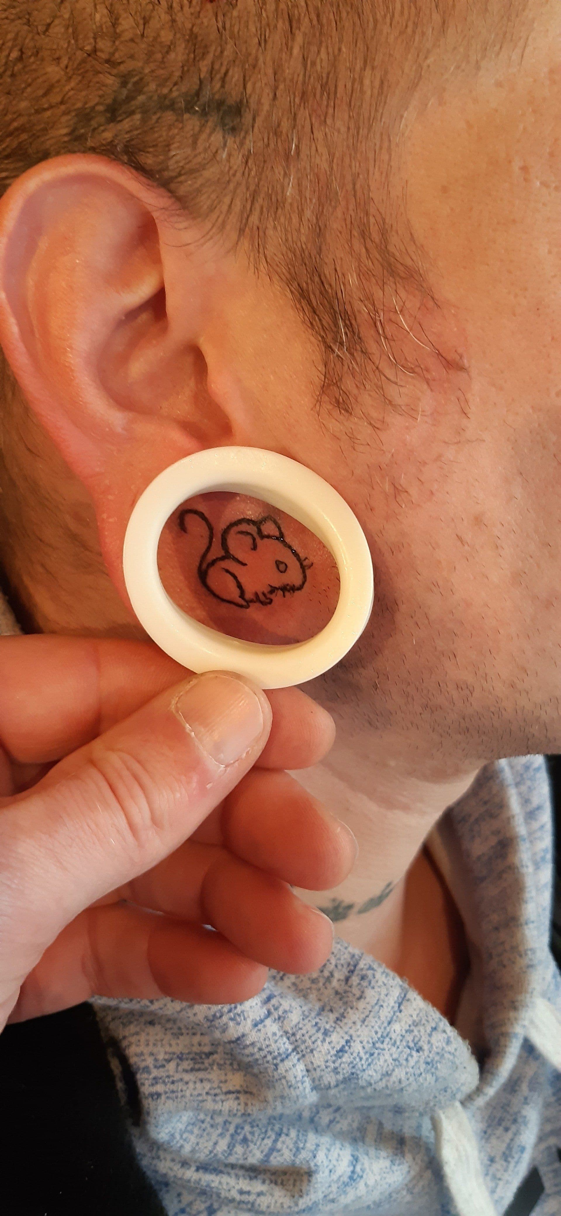 Kleine minimalistische muis tattoo in een opgerekt oorlel.