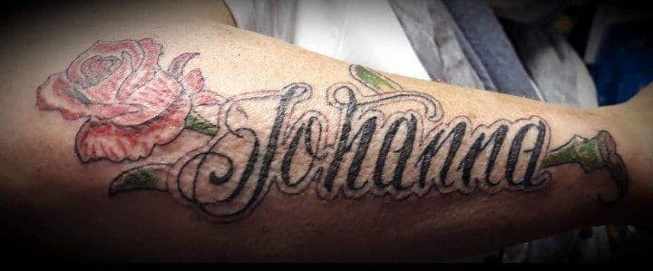 Rode roos met groene steel en de naam 'Johanna' in sierletters op de bovenarm.