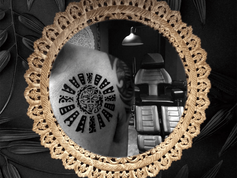 Polynesische zon tattoo op schouder in zwart-wit.