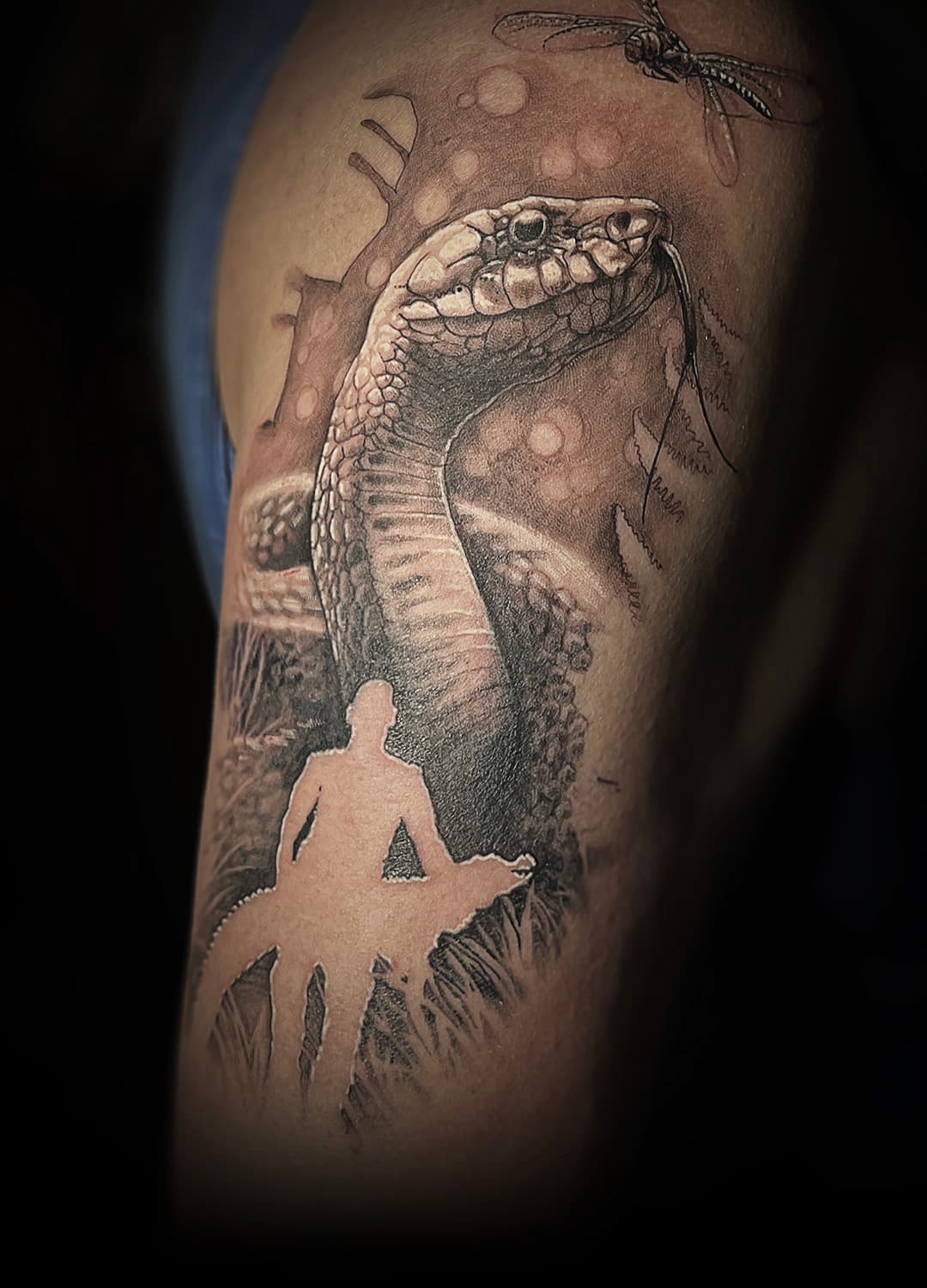 Realistische slang met een silhouet van een persoon en een libelle op de bovenarm.