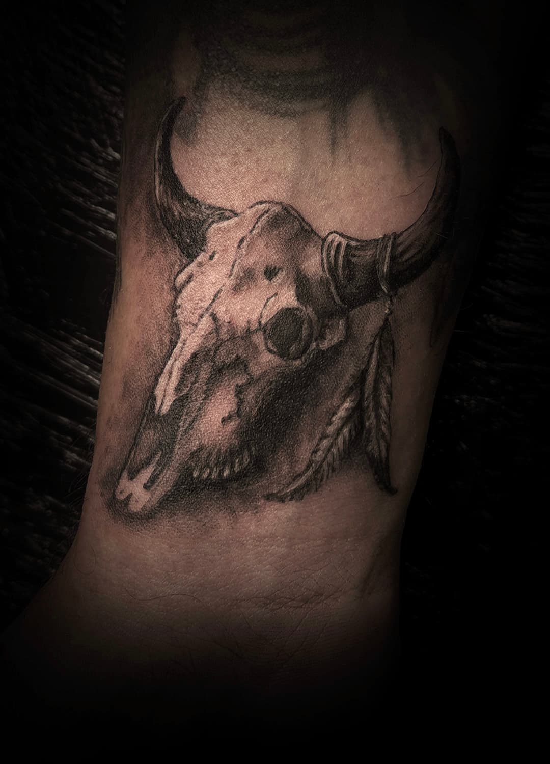 Realistische stierenschedel met veren op de pols.