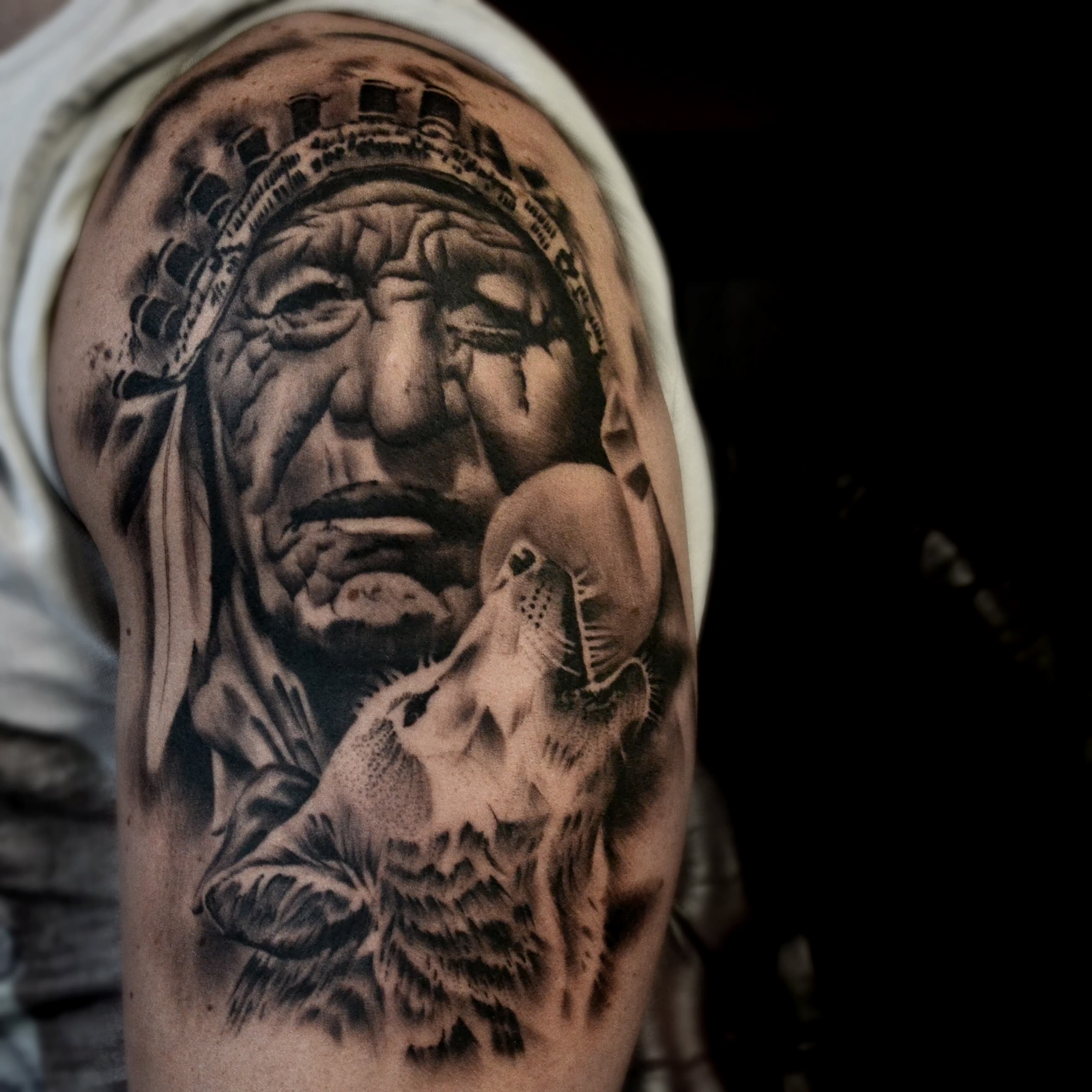 Realistisch portret van een inheemse man met een huilende wolf op de bovenarm.