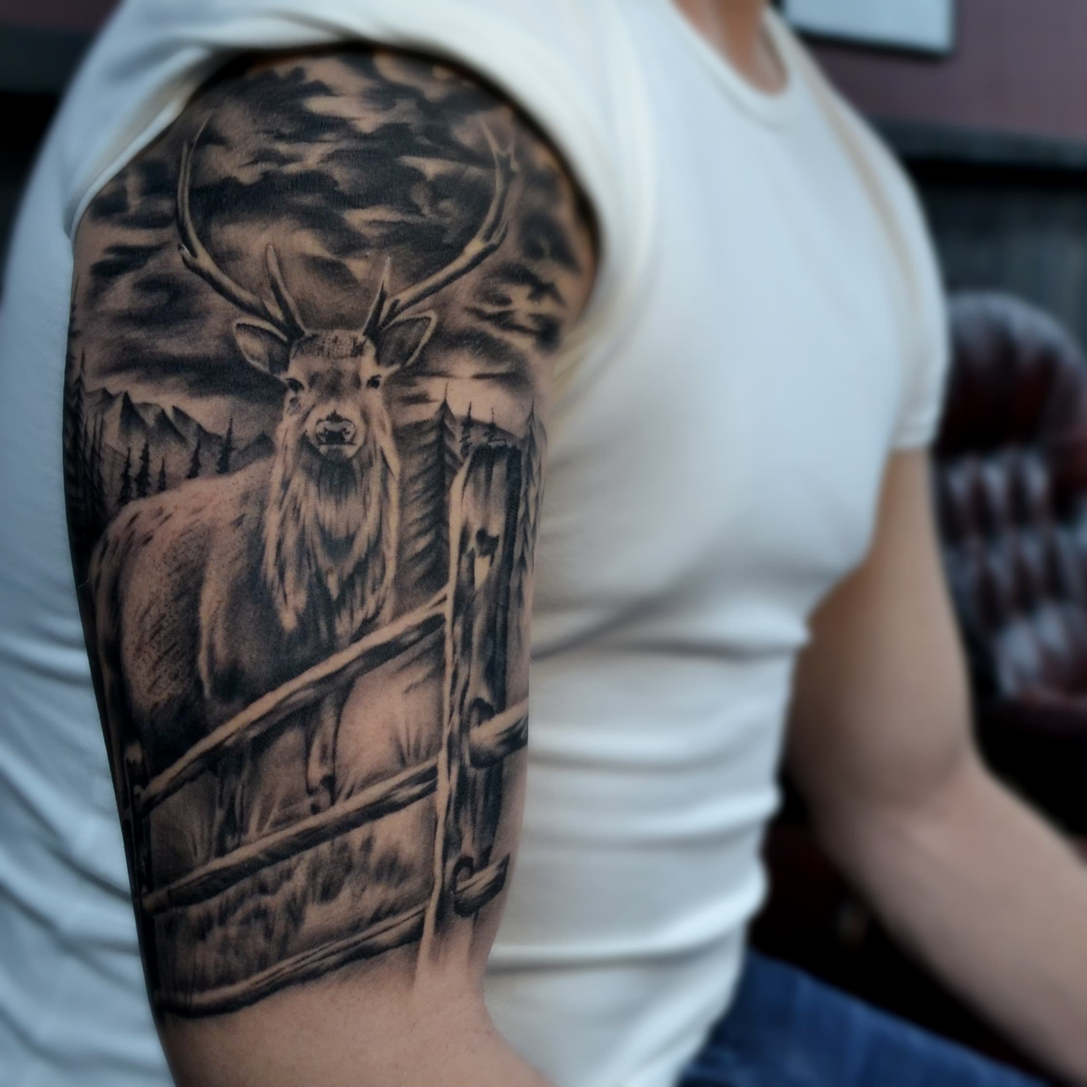 Realistisch hert in landschap op bovenarm.