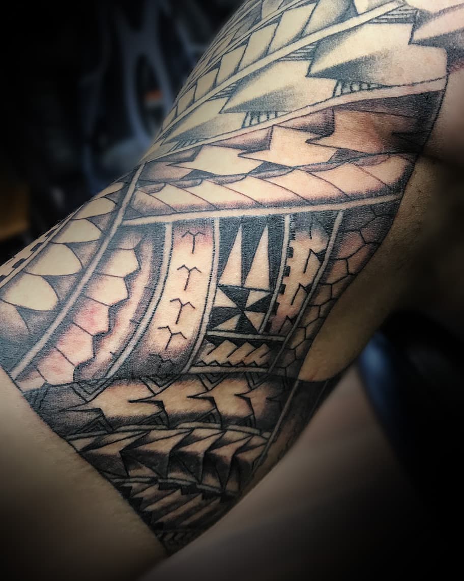 Polynesische tribal tattoo met geometrische patronen op bovenarm.