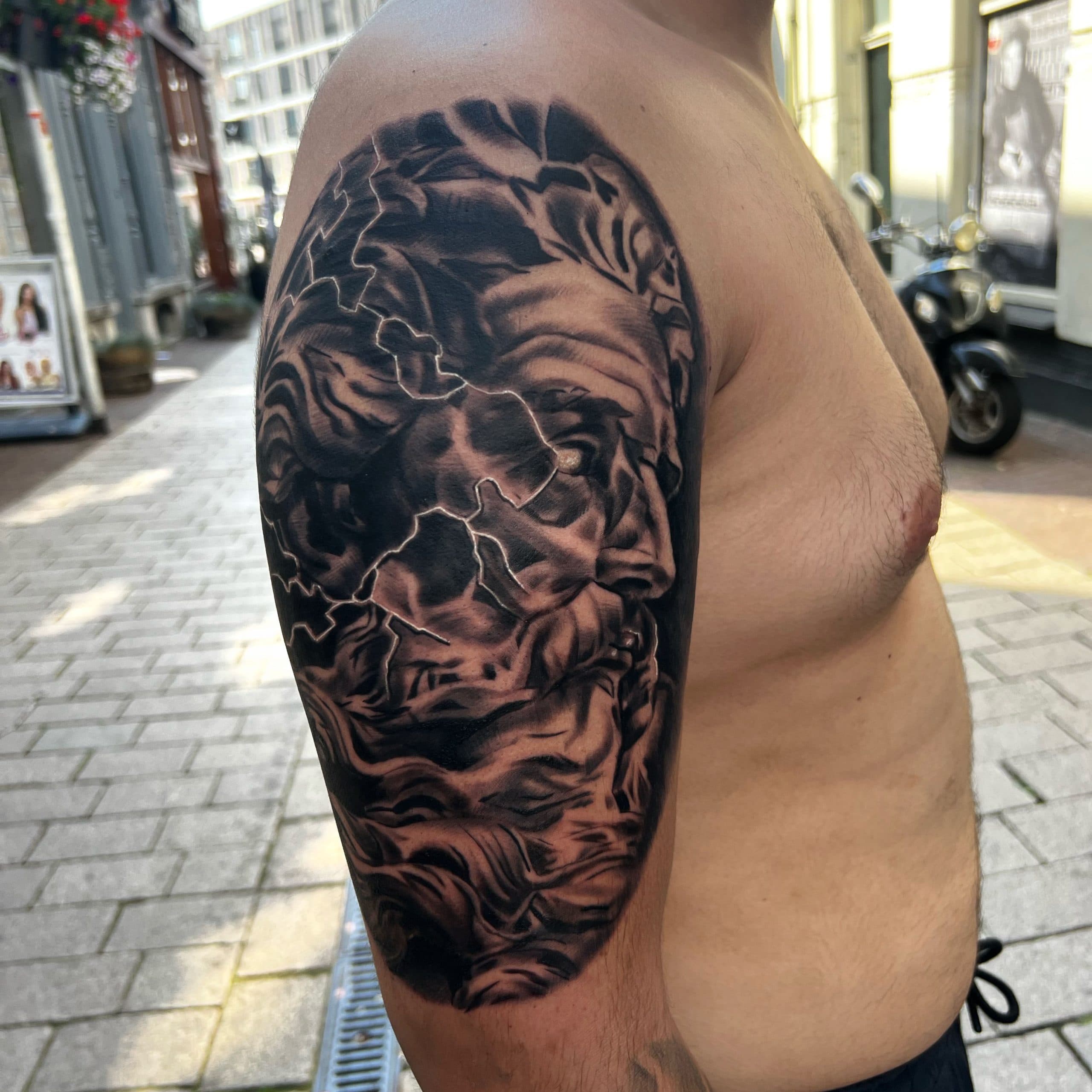 Realistisch portret van Zeus met bliksem op bovenarm.