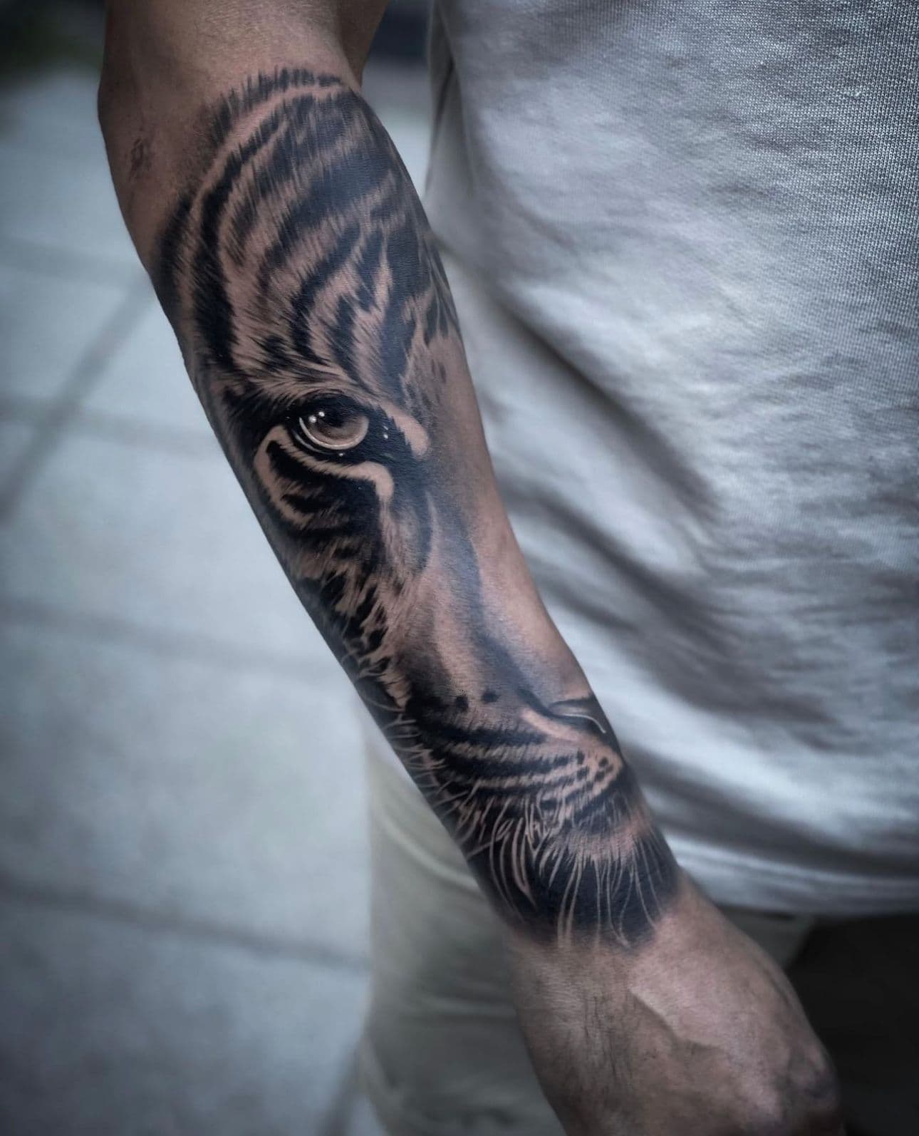 Realistische tijgeroog tattoo op onderarm.