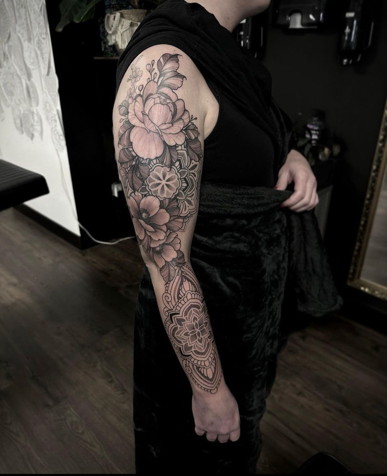 Grote bloemen en mandala sleeve tattoo op de arm.