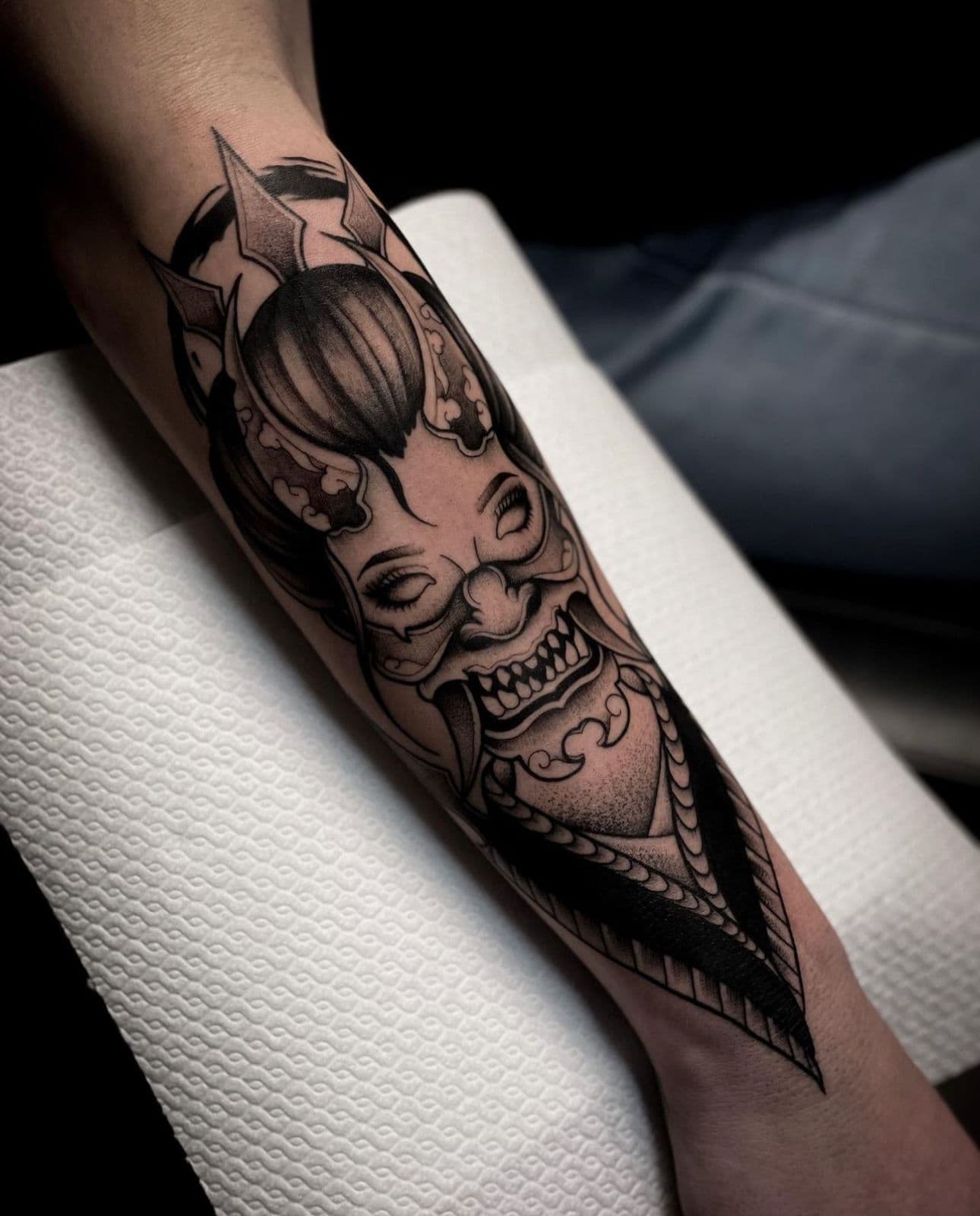 Zwart-wit Hannya masker tattoo op onderarm.